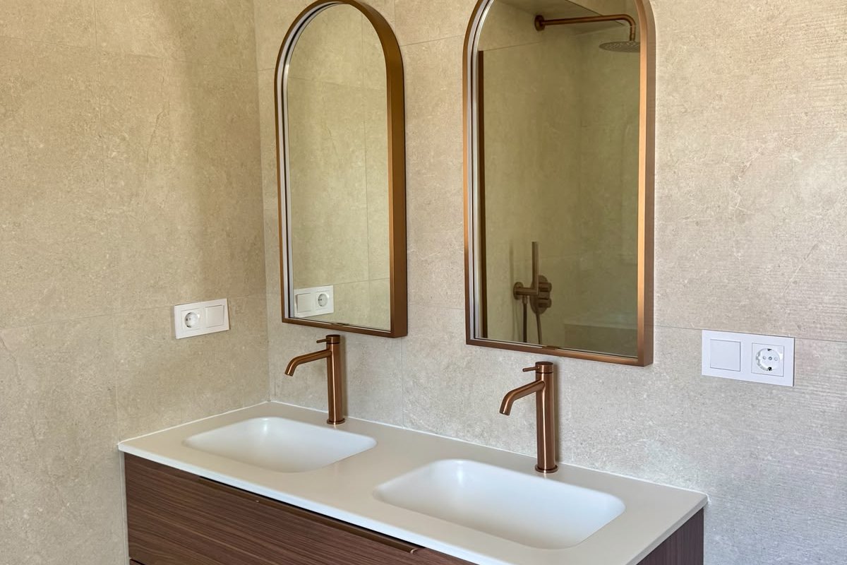 Detailafwerking badkamer met koperen kranen en tegelwerk tot het plafond